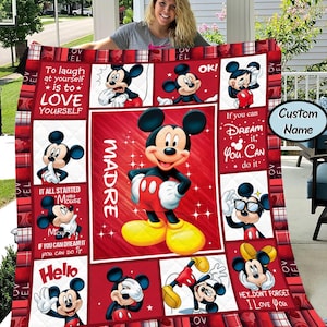 Puede incluir: Una colcha roja y blanca con el tema de Mickey Mouse. La colcha presenta varias im&aacute;genes de Mickey Mouse, junto con texto que dice "To laugh at yourself is to love yourself", "If you can dream it, you can do it" y "Hello".