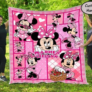 Puede incluir: Colcha rosa de Minnie Mouse con m&uacute;ltiples im&aacute;genes de Minnie Mouse en varias poses. La colcha tiene un patr&oacute;n de cuadros rosas y blancos y un borde blanco. El nombre "Marhea Leelynn" est&aacute; impreso en la colcha.