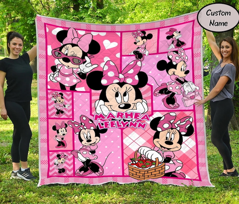 Puede incluir: Colcha rosa de Minnie Mouse con m&uacute;ltiples im&aacute;genes de Minnie Mouse en varias poses. La colcha tiene un patr&oacute;n de cuadros rosas y blancos y un borde blanco. El nombre "Marhea Leelynn" est&aacute; impreso en la colcha.