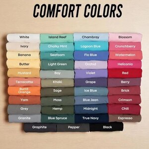 May include: A color chart displaying a variety of fabric swatches in a range of hues, including white, ivory, and black. The text "COMFORT COLORS" is at the top. Each color is labeled with its name, such as "Blossom" and "Espresso".