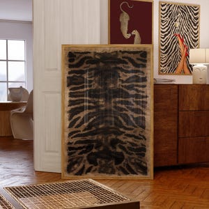 May include: A large rectangular framed wall art piece featuring a dark brown and black tiger stripe pattern. The artwork is displayed vertically, encased in a light-toned wooden frame, showcasing a bold, symmetrical animal print design.