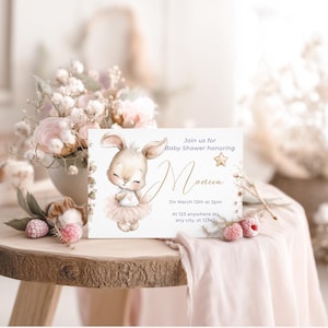 Pu&ograve; includere: Un invito per baby shower con un'illustrazione ad acquerello di un coniglietto con un tut&ugrave; rosa. L'invito include il testo "Unisciti a noi per il baby shower in onore di Monica" e i dettagli dell'evento. &Egrave; posizionato su un tavolo di legno con decorazioni floreali.