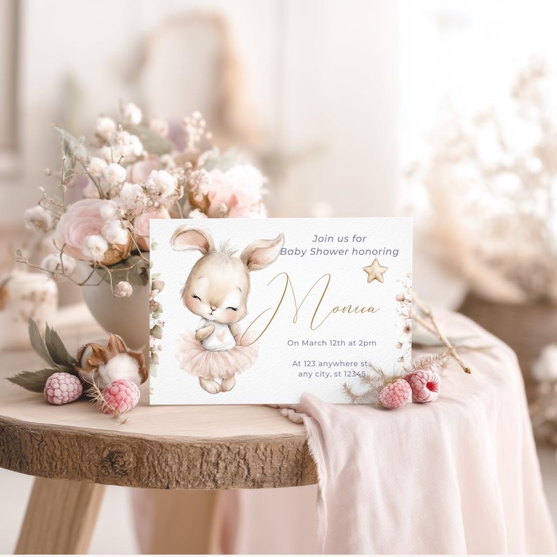Pu&ograve; includere: Un invito per baby shower con un'illustrazione ad acquerello di un coniglietto con un tut&ugrave; rosa. L'invito include il testo "Unisciti a noi per il baby shower in onore di Monica" e i dettagli dell'evento. &Egrave; posizionato su un tavolo di legno con decorazioni floreali.