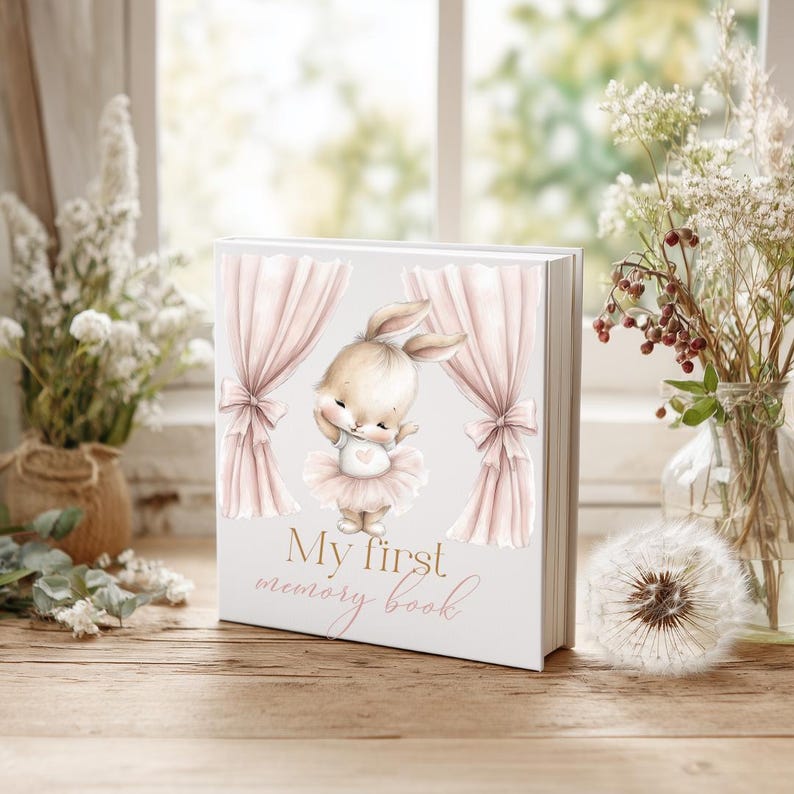 Pu&ograve; includere: Un libro di ricordi bianco con l'illustrazione di un coniglietto con un tut&ugrave;. Il libro presenta tende rosa e la scritta "My first memory book". Un regalo ideale per un neonato, questo libro &egrave; progettato per conservare i ricordi.