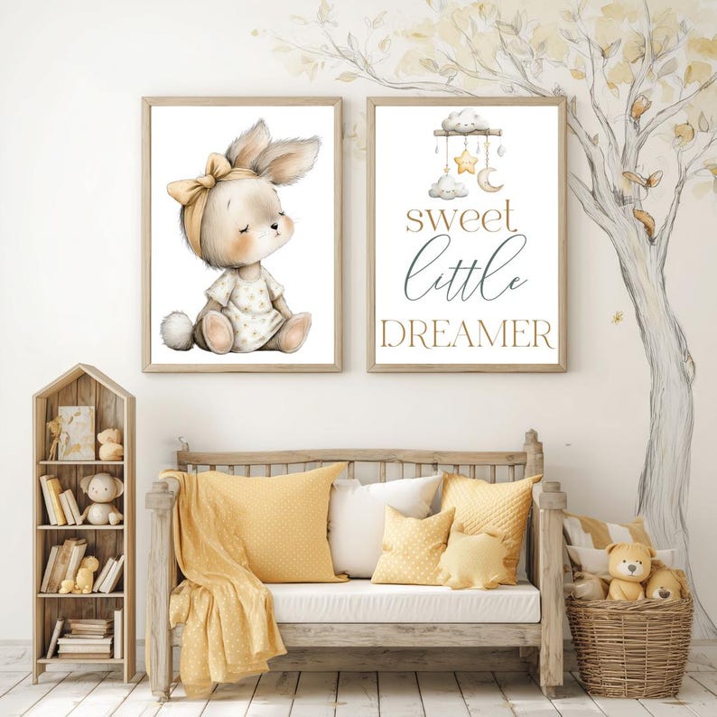 May include: Two framed nursery art prints. One features a bunny wearing a bow, the other reads "sweet little dreamer" with a cloud, moon, and star mobile. The room is decorated in yellow and white tones.