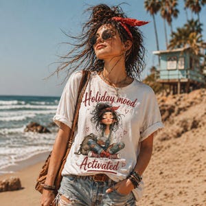 May include: White t-shirt with the text "Holiday mood Activated" and a graphic of a girl sitting cross-legged. The person is wearing sunglasses and a red bandana. The background includes a beach, ocean, and palm trees.