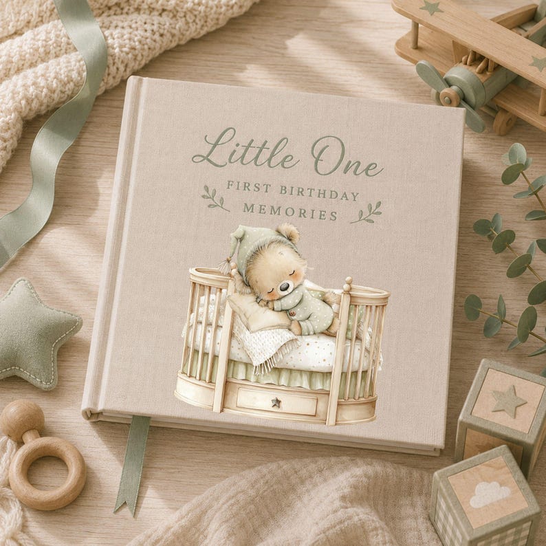 Baby memory book mockup featuring a sleeping sage green teddy bear in a wooden crib, designed for first birthday keepsake albums, nursery gifts and personalised baby photo books.