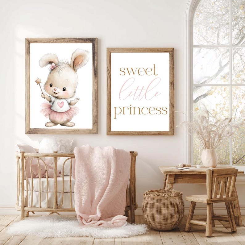 May include: Two framed prints with a nursery theme. One print features a watercolor bunny holding a star wand and wearing a pink tutu. The other print says "sweet little princess" in gold and pink script. A wooden crib and chair are in the foreground.