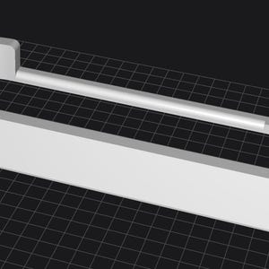 May include: A white, 3D-rendered object with a rectangular base and an arched top. A straight, cylindrical bar extends across the top. A small square cutout is visible on one end. The object is set against a dark, grid-patterned background.