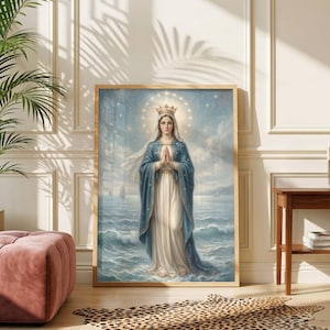 Puede incluir: Una impresión enmarcada de una figura religiosa, representada con un halo y una corona, de pie frente a un paisaje marino. La figura lleva una capa azul sobre un vestido blanco. La obra de arte está en un marco de madera, exhibida en una pared con un otomán rosa y una alfombra con estampado de leopardo.