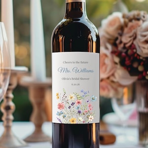 May include: A wine bottle with a custom label for Olivia's Bridal Shower. The label features the text "Cheers to the future Mrs. Williams" and the date 6.20.26. A floral design with colorful flowers decorates the bottom of the label.