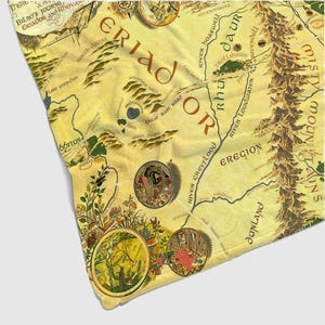 May include: A detailed map of Eriador and Rhovanion, featuring geographical details like rivers, mountains, and forests. The map is in shades of yellow and brown, with decorative circular illustrations. Text includes place names and the phrase "Bilbo's Journey".