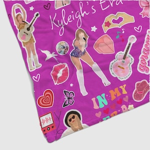 May include: A magenta blanket featuring various illustrations, including a singer, guitars, hearts, and butterflies. The blanket has the text "Kyleigh's Era" and "In My". The design is a collage of pop culture elements.