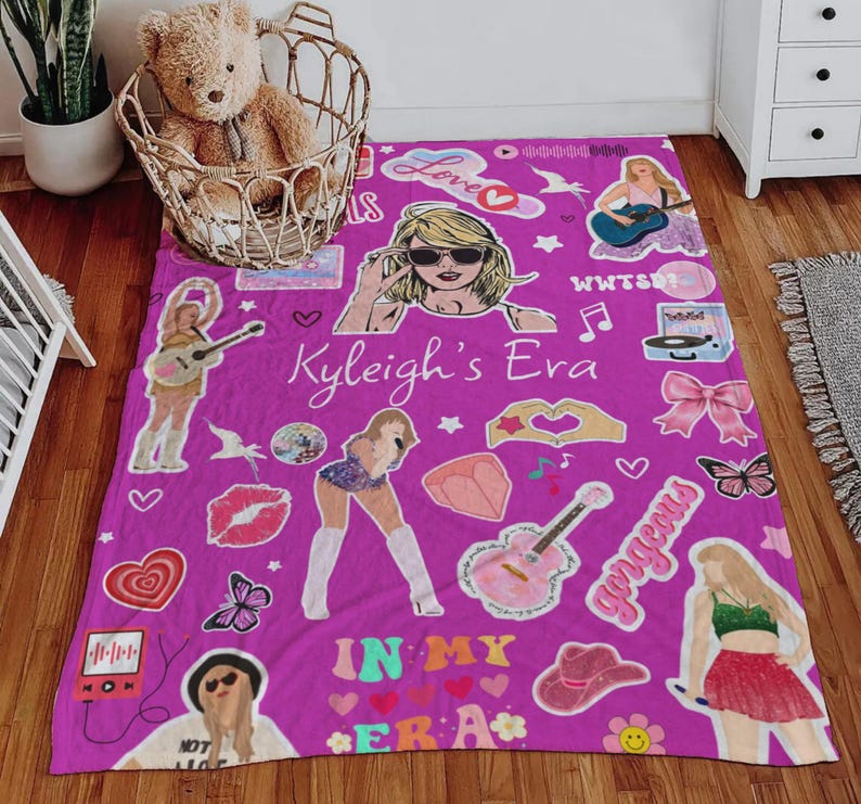 May include: A vibrant purple blanket featuring various illustrations and text, including a woman wearing sunglasses, guitars, hearts, and the words "Kyleigh's Era" and "In My Era".