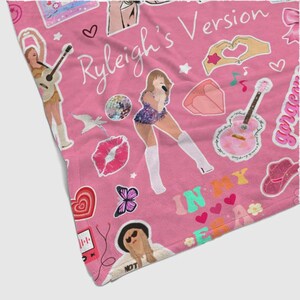 May include: Pink blanket with a repeating pattern of illustrations and text. The design includes images of a woman singing, guitars, hearts, butterflies, and the words "Ryleigh's Version" and "In My Era."