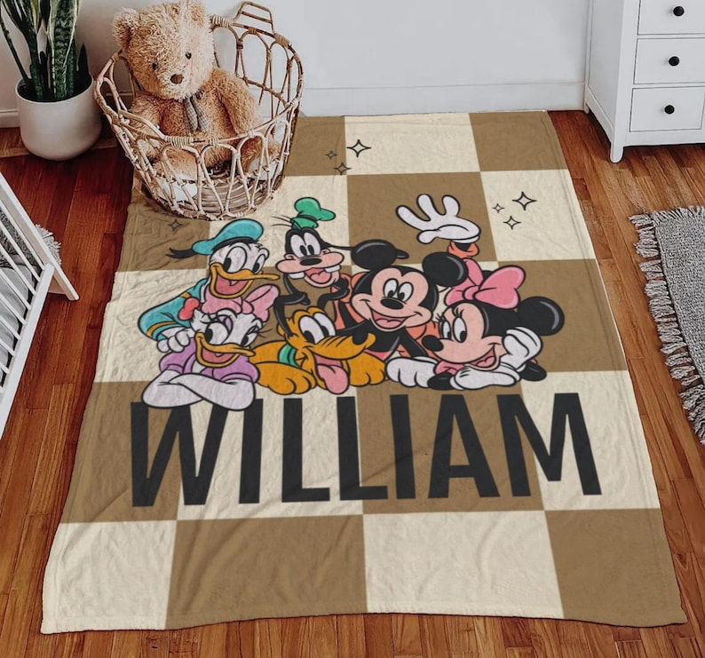 Puede incluir: Una manta a cuadros marr&oacute;n y beige con personajes de dibujos animados de Disney, incluyendo Mickey y Minnie Mouse, Donald y Daisy Duck, Goofy y Pluto. El nombre "WILLIAM" est&aacute; impreso en letras negras grandes.