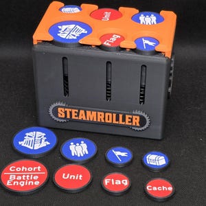 May include: A black and orange Steamroller game piece holder with various blue and red tokens. The tokens are labeled with words like "Unit", "Flag", and "Cache", and feature icons. The Steamroller logo is displayed on the front.