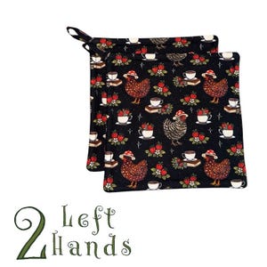 May include: Two black pot holders with a whimsical pattern of chickens wearing hats, teacups, strawberries, and books. The pot holders have a loop for hanging. The text "2 Left Hands" is at the bottom.