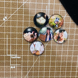 Peut inclure: Six aimants photo ronds en verre avec des images diff&eacute;rentes. Les images comprennent un chat, un enfant, un b&eacute;b&eacute;, une femme en robe de graduation, une femme en robe et un couple.