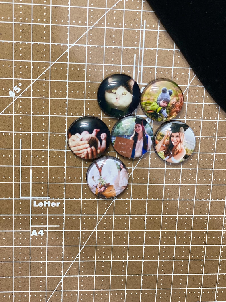 Peut inclure: Six aimants photo ronds en verre avec des images diff&eacute;rentes. Les images comprennent un chat, un enfant, un b&eacute;b&eacute;, une femme en robe de graduation, une femme en robe et un couple.