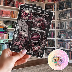 May include: A black tablet case with a skull, roses, and text such as "Reading is my foreplay" and "Tattoo warnings". The design incorporates a skull with a butterfly, and the overall aesthetic is dark and gothic. The case is designed for a tablet.
