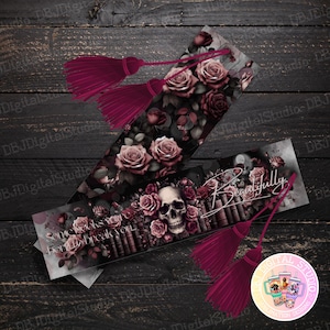 May include: Two bookmarks with a dark background featuring a skull, roses, and the text "Some books were born to break you" and "Beautifully". The bookmarks have burgundy tassels.