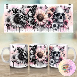 May include: Two white mugs with a design featuring a black and white skull with pink and white flowers, butterflies, and the text "You got This!"