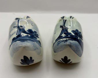 Vintage Delaware Dutch shoes ashtrays featuring a white and blue design . one of the shoes has some crazing inside  6” L