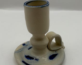Könnte beinhalten: Ein weißer Kerzenhalter aus Keramik mit blauem Rand und blauen Blattmotiven. Der Halter hat einen Griff und einen Sockel.