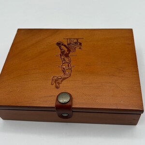 Caixa de baralho de madeira vintage com um jogador de basquete no topo da caixa com 2 baralhos de cartas dentro e um pequeno lascado de madeira no topo 6” L x 4