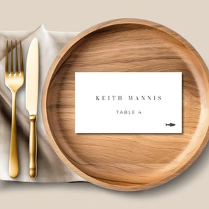 May include: A white place card with the text "Keith Mannis Table 4" and a small fish icon on a wooden plate.