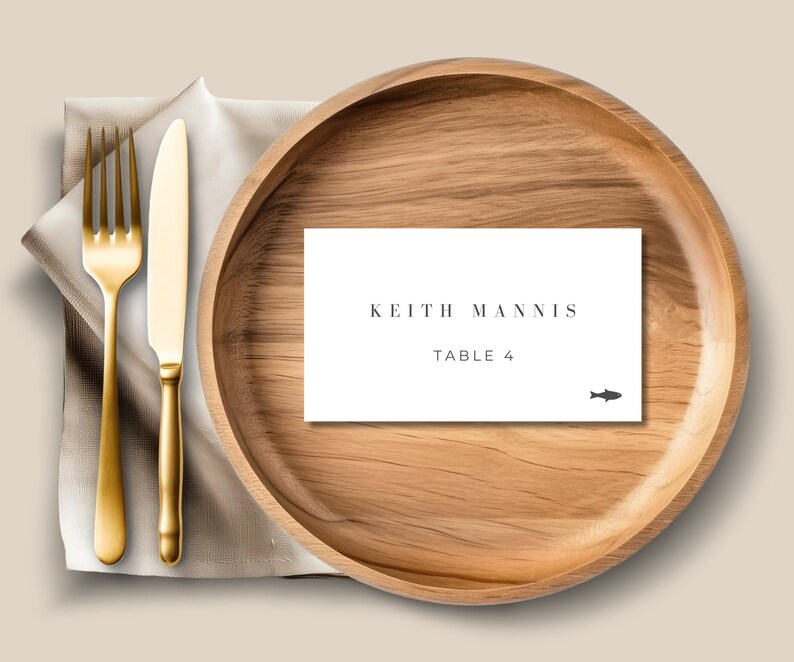 May include: A white place card with the text "Keith Mannis Table 4" and a small fish icon on a wooden plate.