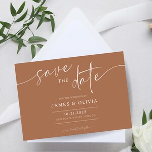 Może przedstawiać: Brązowa karta z zaproszeniem na ślub z białą kaligrafią, która głosi "Save the Date" i zawiera imiona James & Olivia, datę 10.21.2023 i lokalizację Applegate Valley, Oregon.