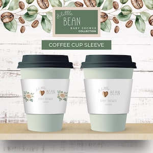 May include: Two light green coffee cups with black lids, each featuring a white paper sleeve. The sleeves are printed with the text A little BEAN BABY SHOWER, a coffee bean graphic, and floral illustrations in soft beige and green tones.