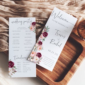 May include: Two wedding ceremony cards with a floral design. The first card lists the wedding party and the second card says "Welcome to the wedding of Travis + Rachel 10.21.2X".