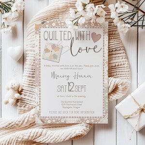 May include: A baby shower invitation with the text "Quilted with Love" and a patchwork design. The invitation is surrounded by white flowers, a white heart, a small teddy bear, and a wrapped gift.