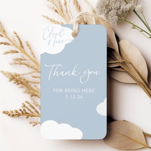 May include: A light blue gift tag with the text "We're on Cloud Nine" and "Thank you for being here 5.12.24". The tag has a cloud design and is tied with a natural twine.