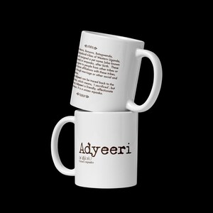 May include: Two white ceramic mugs, one stacked on the other. The top mug features text explaining the name "Adyeeri". The bottom mug displays "Adyeeri" in a bold font, with phonetic pronunciation.