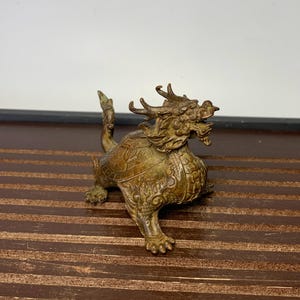 May include: A bronze dragon statue with intricate details. The dragon is depicted with a fierce expression and a long, winding tail. The statue is a traditional Chinese design and is a popular collectible.