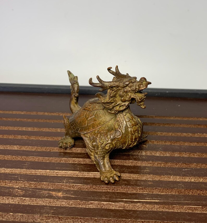 May include: A bronze dragon statue with intricate details. The dragon is depicted with a fierce expression and a long, winding tail. The statue is a traditional Chinese design and is a popular collectible.