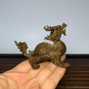 May include: A bronze sculpture of a dragon turtle, a mythical creature with the head of a dragon and the body of a turtle. The sculpture is detailed and intricate, with scales and claws visible. The dragon turtle is a symbol of longevity and good luck in Chinese culture.