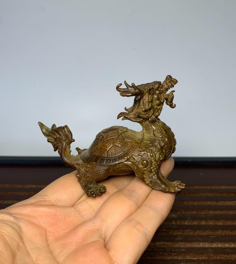 May include: A bronze sculpture of a dragon turtle, a mythical creature with the head of a dragon and the body of a turtle. The sculpture is detailed and intricate, with scales and claws visible. The dragon turtle is a symbol of longevity and good luck in Chinese culture.