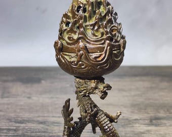 May include: Bronze incense burner featuring a dragon base supporting a detailed, flame-shaped top. The intricate design showcases a dragon with detailed scales and a textured, openwork top, creating a unique decorative piece.