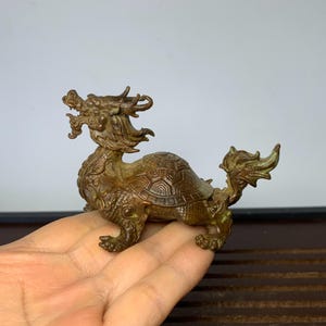 May include: A bronze dragon turtle figurine. The dragon is depicted with a long, flowing mane and a fierce expression. The turtle shell is detailed with intricate carvings.