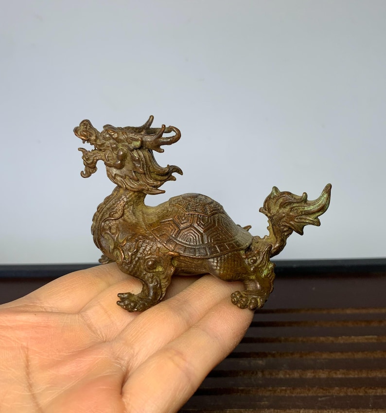 May include: A bronze dragon turtle figurine. The dragon is depicted with a long, flowing mane and a fierce expression. The turtle shell is detailed with intricate carvings.