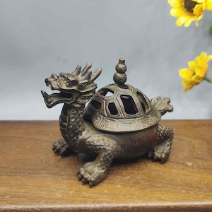 以下が含まれることがあります： ブロンズ製のドラゴンのカメの香炉。 ドラゴンのカメは、詳細なドラゴンの頭と幾何学的な切り欠きのあるカメの甲羅を持っています。 バーナーには小さな装飾的な上部があります。