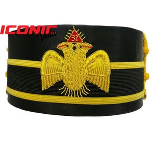 Puede incluir: Sombrero masónico negro y dorado con un águila bordada en oro y un triángulo rojo con el número 32 en su interior.