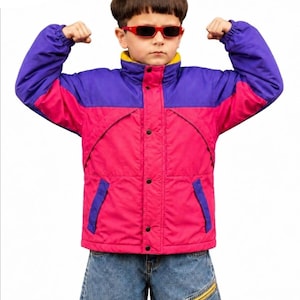 May include: A color-blocked jacket featuring a bright pink torso and purple sleeves with a high collar lined in yellow. The jacket has a front zipper closure covered by a snap-button placket, two side pockets, and elastic cuffs. The jacket is worn with blue denim jeans that feature a visible yellow zippered pocket on the thigh.