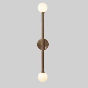 May include: A brass wall sconce with two frosted glass globes. The sconce has a long, vertical stem and a circular base.