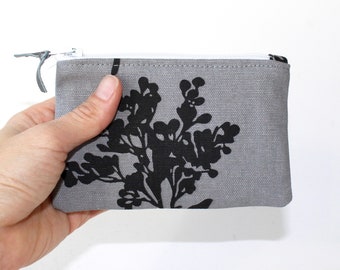 Petite pochette zippée. Petit porte-monnaie à fermeture éclair. Petit sac zippé gris avec branches et fleurs noires et blanches